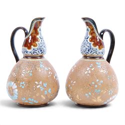 Pair of Doulton Lambeth ewers, decorated with a lace-impressed body decorated with floral ...
