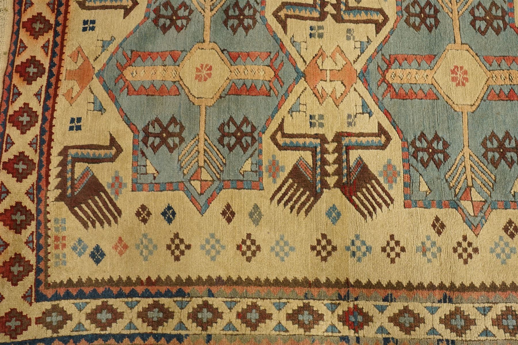 Two Caucasian designed rugs comprising a flatweave and hand-knotted rug, Caucasian design flatweave, cream ground with three large blue geometric medallions surrounded by stylised birds and geometric motifs, enclosed by repeating geometric border, fringed ends, H176cm, W102cm; hand-knotted Caucasian rug, ivory ground with three polychrome octagonal medallions surrounded by stylised animals, flowerheads and geometric motifs, enclosed by salmon pink geometric border, fringed ends, H163cm, W106cm
