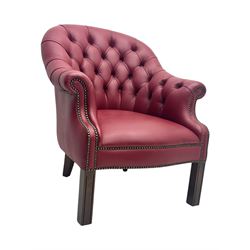 Kingsgate - contemporary 'Devon' bucket armchair, upholstered in red leather with buttoned backrest, rolled arms and brass stud detailing, raised on four dark wood supports with vertical carving
