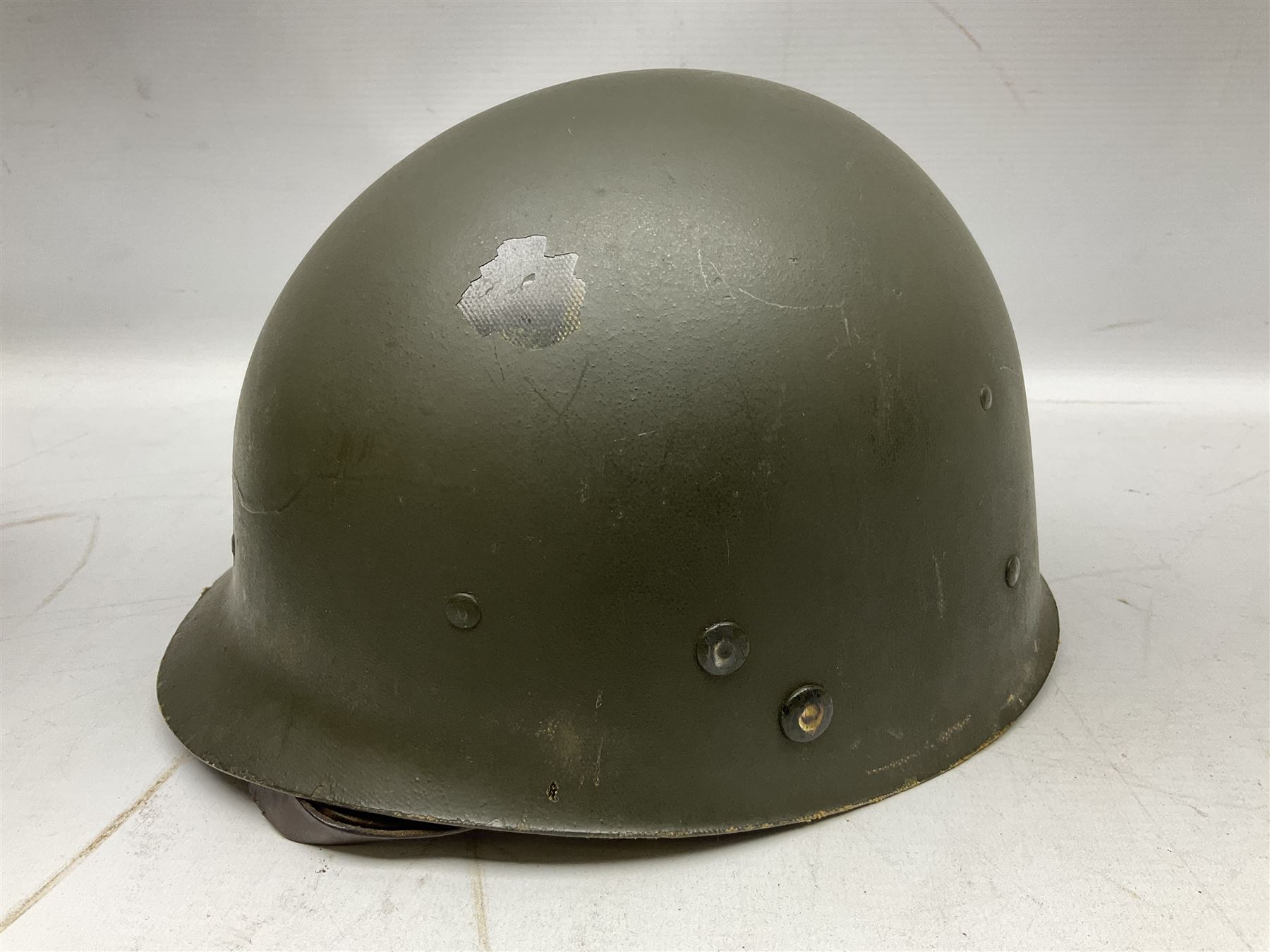 American first type paratrooper helmet with post-WW2 strap and D-rings and later 1944 liner bearing Firestone Tyre and Rubber Company mark; green textured finish