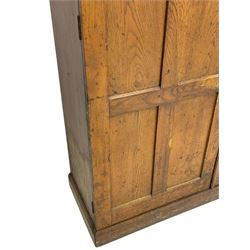 The North of England School Furnishing Company Limited Darlington - early 20th century oak school cupboard, projecting moulded cornice over two panelled doors, fitted with shelves, on chamfered plinth base 