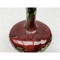 Three Minton Secessionist vases, with tube-lined stylised flower decoration, two upon a red ground and third upon a purple ground, all with printed mark to base 'Minton Ltd, No. 33', H13cm