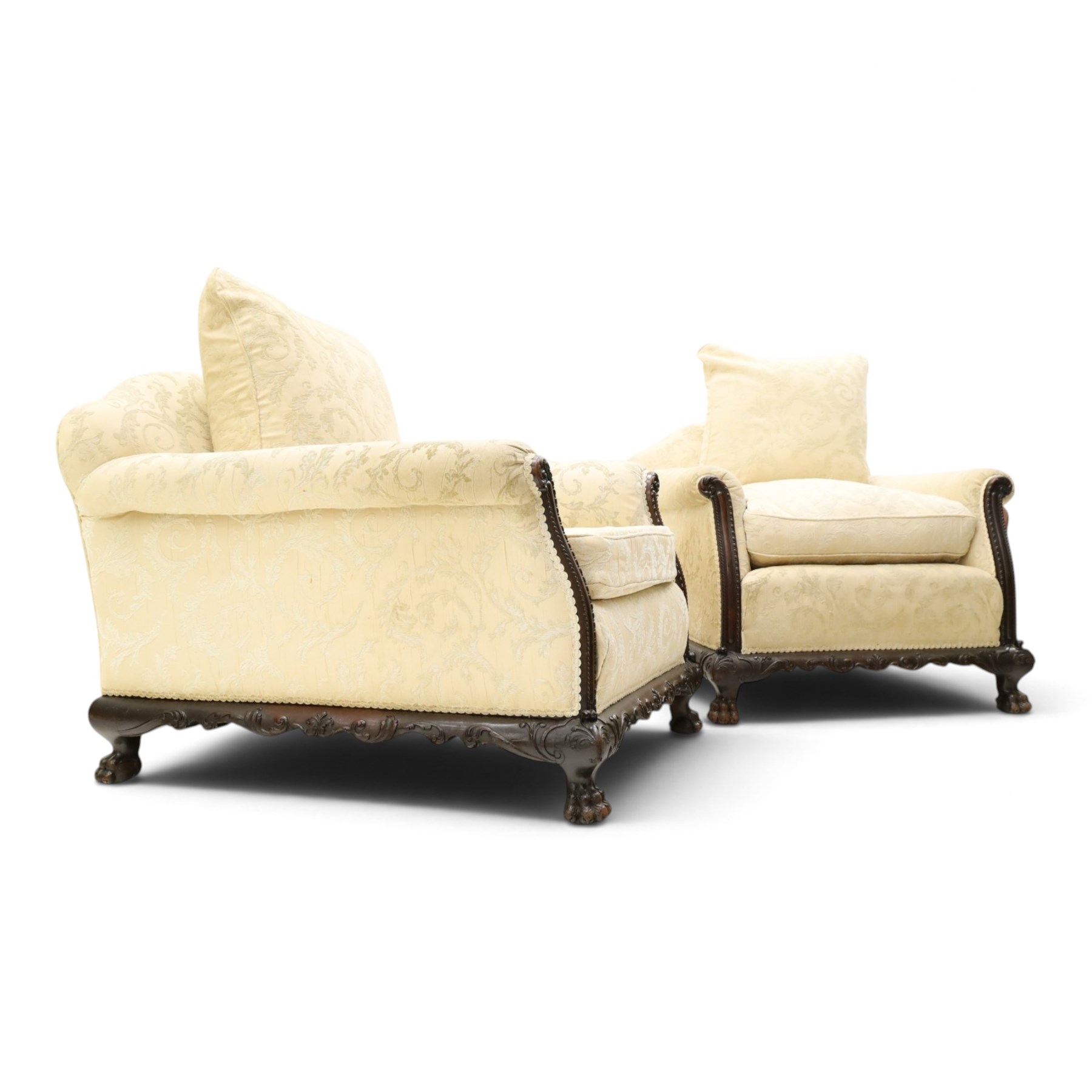 Quality Edwardian carved mahogany lounge suite comprising three-seater settee and pair of armchairs, the sofa with arched back over rolled arms and deep sprung seat, the arm terminals carved with acanthus rosette over gadroon and rope-twist moulding, the shaped apron carved and moulded with scrolling foliate acanthus motifs, terminating to four large front hairy paw and ball feet, upholstered in pale yellow foliate fabric with matching seat and scatter cushions (W200cm D105cm H73cm); the matching deep armchairs (W78cm D95cm H75cm)