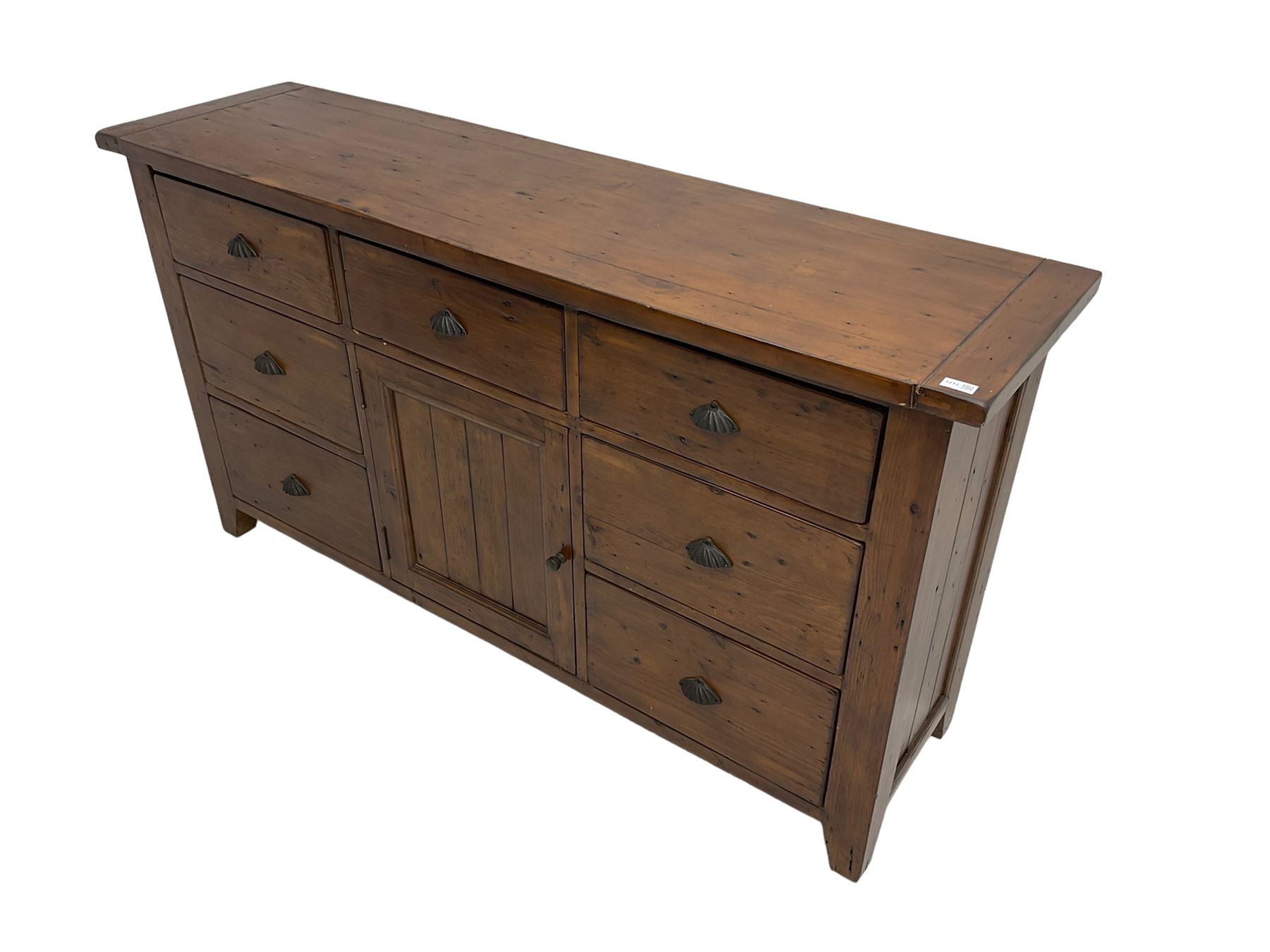Stained pine rustic sideboard, rectangular top over seven drawers and single panelled cupboard, fitted with shell handles