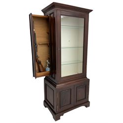 Mahogany display cabinet with hidden compartment, projecting cornice over single glazed door enclosing glass shelves, double panelled cupboard below, the interior with button releasing sliding back compartment, on bracket feet