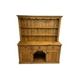 20th century pine dresser, projecting cornice with shaped frieze over two plate racks, lower section fitted with three drawers and two cupboards, on plinth base
