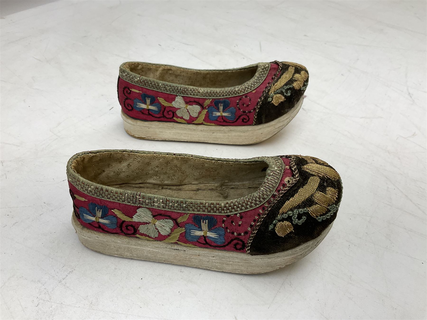 French silver plated wine taster of typical form, stamped, together with a silver plated napkin ring, and an 'Alpaca Silver' pill box with mother of pearl detailed cover, (3) together with Two pairs of late 19th/early 20th century Chinese Lotus shoes for binding feet, the first with purple silk heavily embroidered with ornate floral motifs, L10cm the second larger fuschia and black pair with thicker sole embroidered with flowers, L14cm