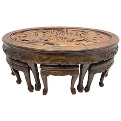 Chinese carved hardwood coffee table with six inset stools or side tables, oval top carved with figures and traditional pagoda scenes, with matching carved frieze, raised on tapering supports with paw feet