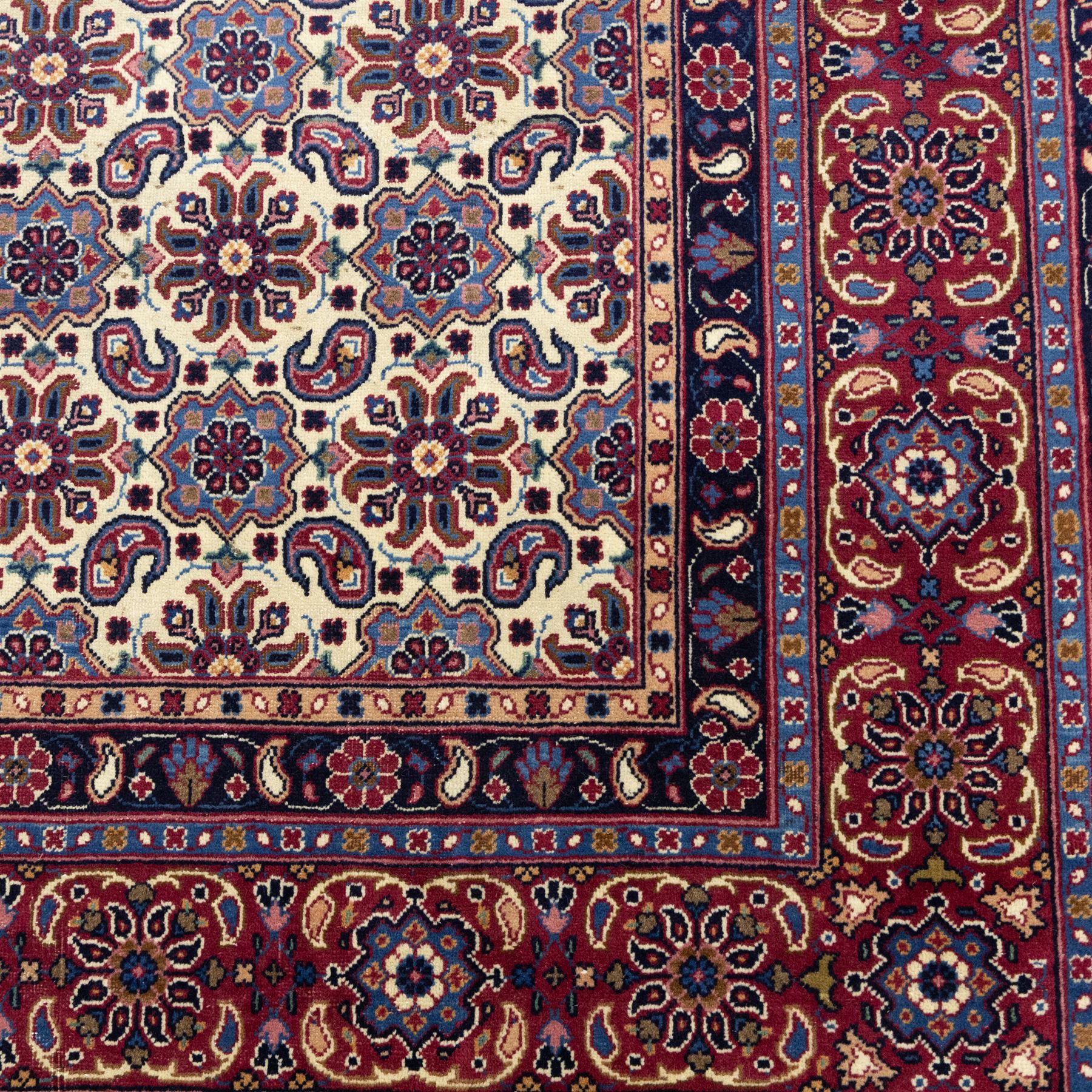 North West Persian Tabriz hand-knotted carpet, ivory field densely decorated with an all-over Herati style (Mahi) lattice composed of stylized rosettes and scrolling leaves, enclosed by a broad madder-red border of palmette and floral vine design, between navy guard stripes, cotton fringe ends 
