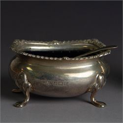 Mid 20th century silver three piece cruet set, comprising pepper shaker, open salt, mustard pot with cover and two condiment spoons, all of oval form with oblique gadrooned rims and upon four paw feet, hallmarked Adie Brothers Ltd, Birmingham 1957, with blue glass liners