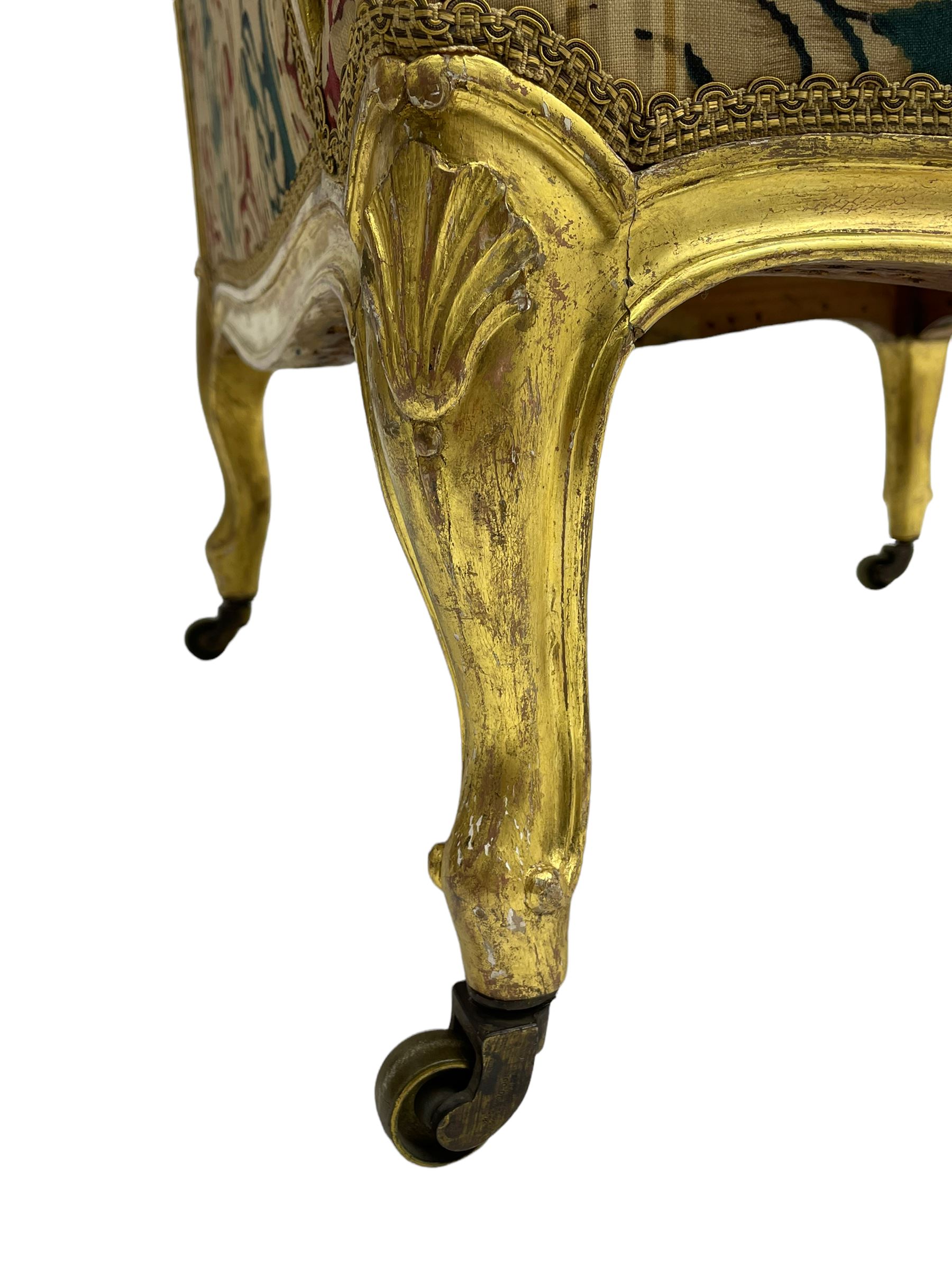 William Bertram & Son of London - pair late 19th century giltwood armchairs, moulded frame with scroll carved back and arm terminals, upholstered in striped fabric with foliate pattern, on shell carved cabriole supports, the brass castors stamped 