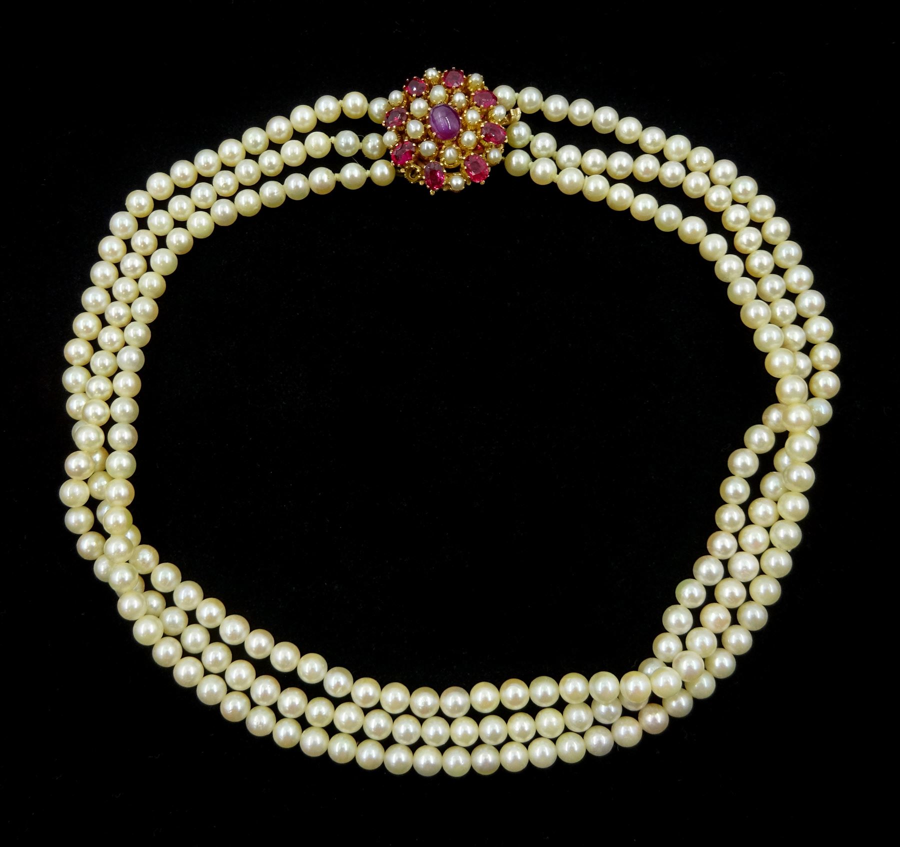 Three strand cultured pearl, with 14ct gold oval cabochon and oval facet ruby and pearl clasp