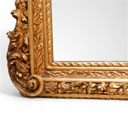Victorian design gilt framed wall mirror, scrolling shell pediment with curled acanthus leaves flanked by seated putti, the moulded frame decorated with trailing leafy motifs, enclosing bevelled plate, curled acanthus leaf lower corner brackets 