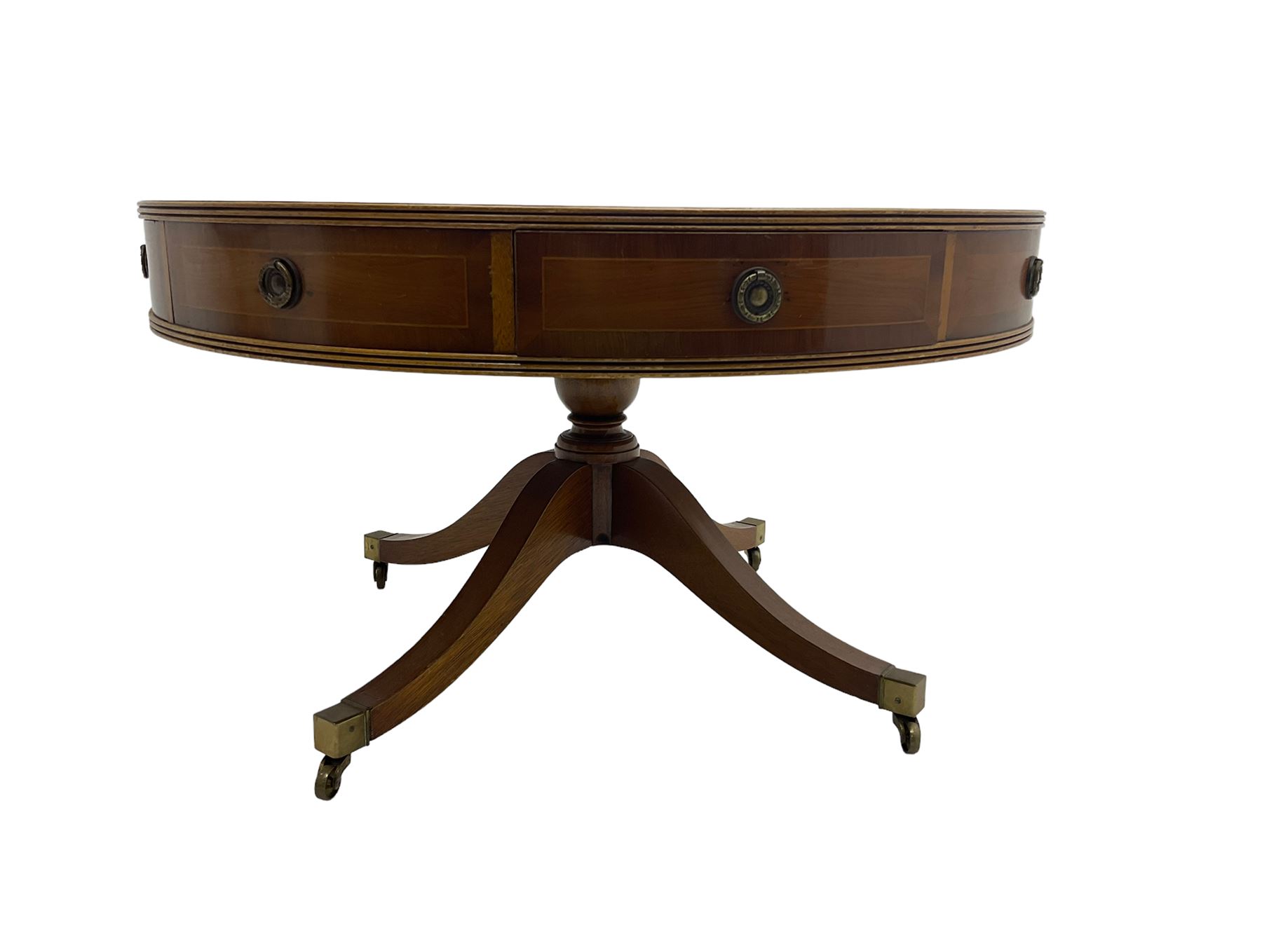 Georgian style yew wood drum table, circular top with green and tooled leather inset, fitted with four drawers, on turned pedestal base with four splayed supports, brass cups and castors