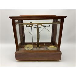 Set of brass balance scales in glazed mahogany case, with frieze drawer opening to reveal boxed weights, raised on four brass screw feet, H45cm W45.5cm D22.5cm