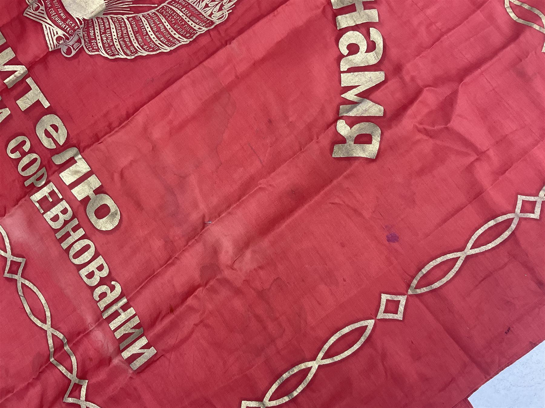 1970s Soviet banner printed in gold on a red ground, roughly translates as 'Transferable Banner - To the winner in the Socialist Competition' and 'Work Study Live by Communism' verso; wreath of wheat ears to either side; tassels on three sides 110 x 155cm