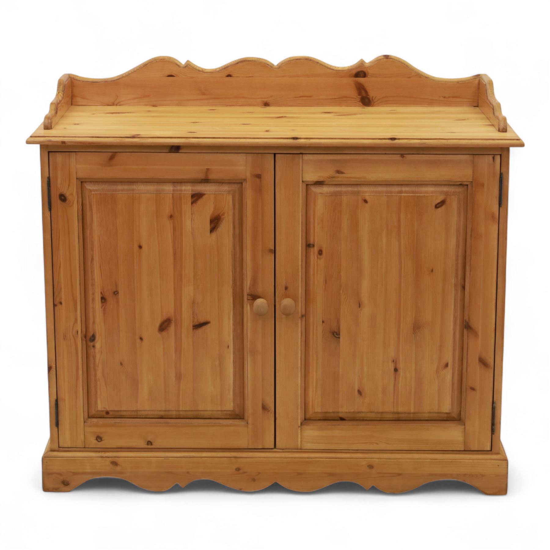 Contemporary pine cupboard, with raised shaped gallery over plain top, panelled double doors below with turned knob handles, shaped apron and plinth base