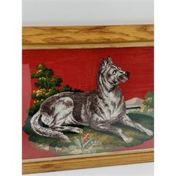 A framed and glazed wool work and bead work picture, depicting a dog within a part landscape setting, upon a red ground, including frame H49 L69.5cm.