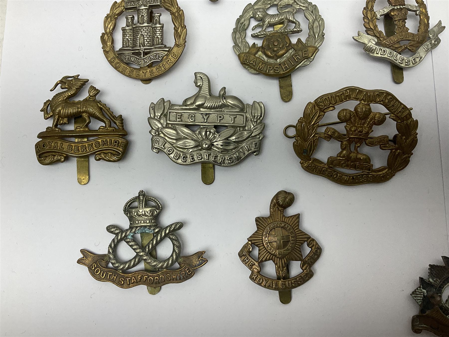 Seventeen regimental cap badges including Dorsetshire, Worcestershire, Staffordshire, Lancashire, Manchester, Middlesex, Berkshire, Bedfordshire etc (17)