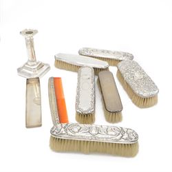 Group of silver mounted dressing table items, to include dwarf candlestick, with embossed ribbon decoration, comb holder, jar lid and six clothes brushes, all hallmarked 
