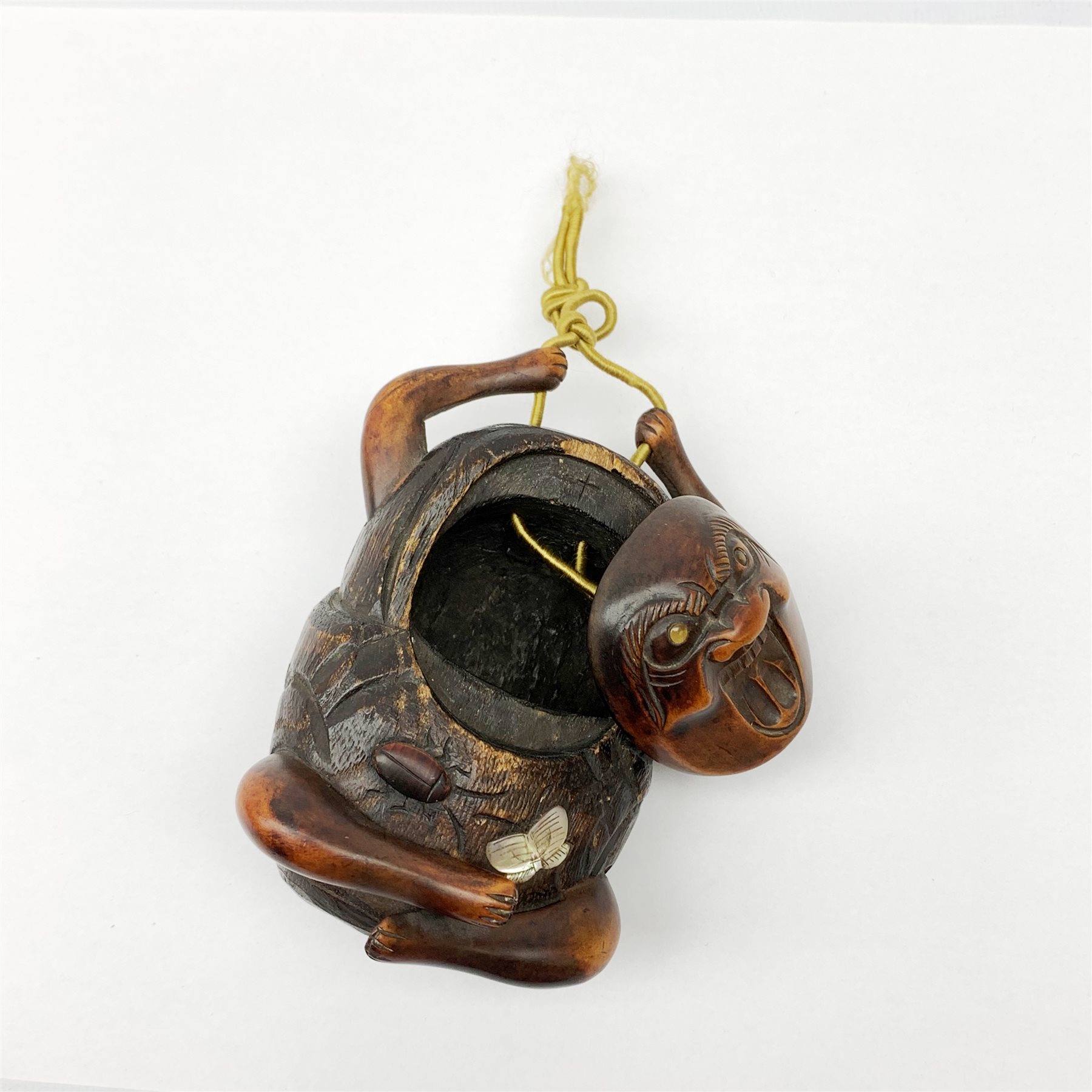 A Japanese carved soft wood inro, modelled as a streching and yawning figure, possibly Daruma, detailed with insect, inset mother of pearl butterfly, and glass eyes, H10cm. 