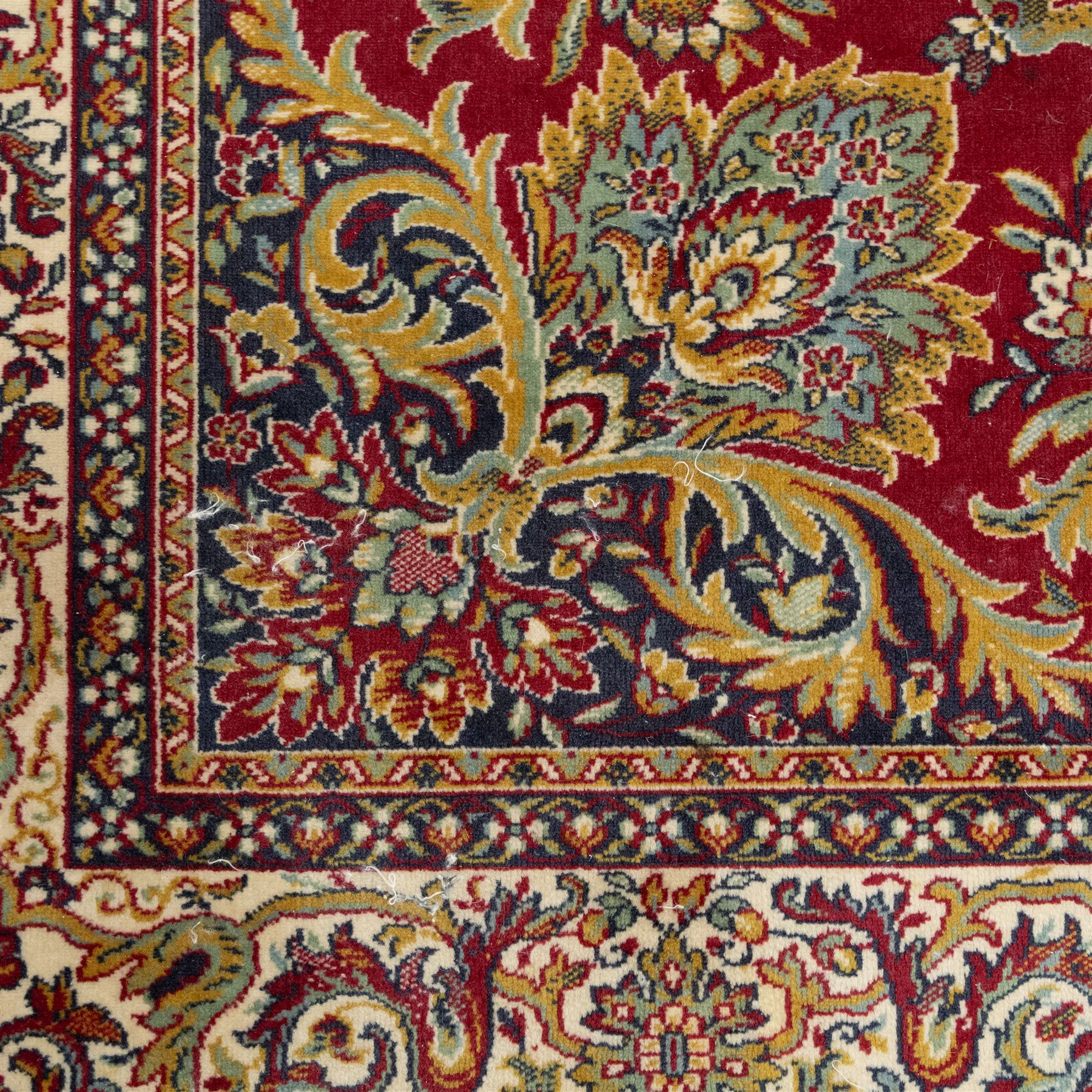 Kashan design carpet, crimson field with central medallion and scrolling floral sprays, cream and polychrome palmette and scrolling vine borders  