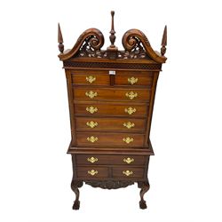 Chippendale style mahogany finish chest on chest, broken swan neck pediment with pierced foliate design over fretwork cornice, upper section fitted with two short and three long drawers flanked by chamfered and foliate carved uprights, bottom section with three drawers over cartouche apron with pierced trailing foliate motif, raised on scroll carved cabriole supports with ball and claw feet
