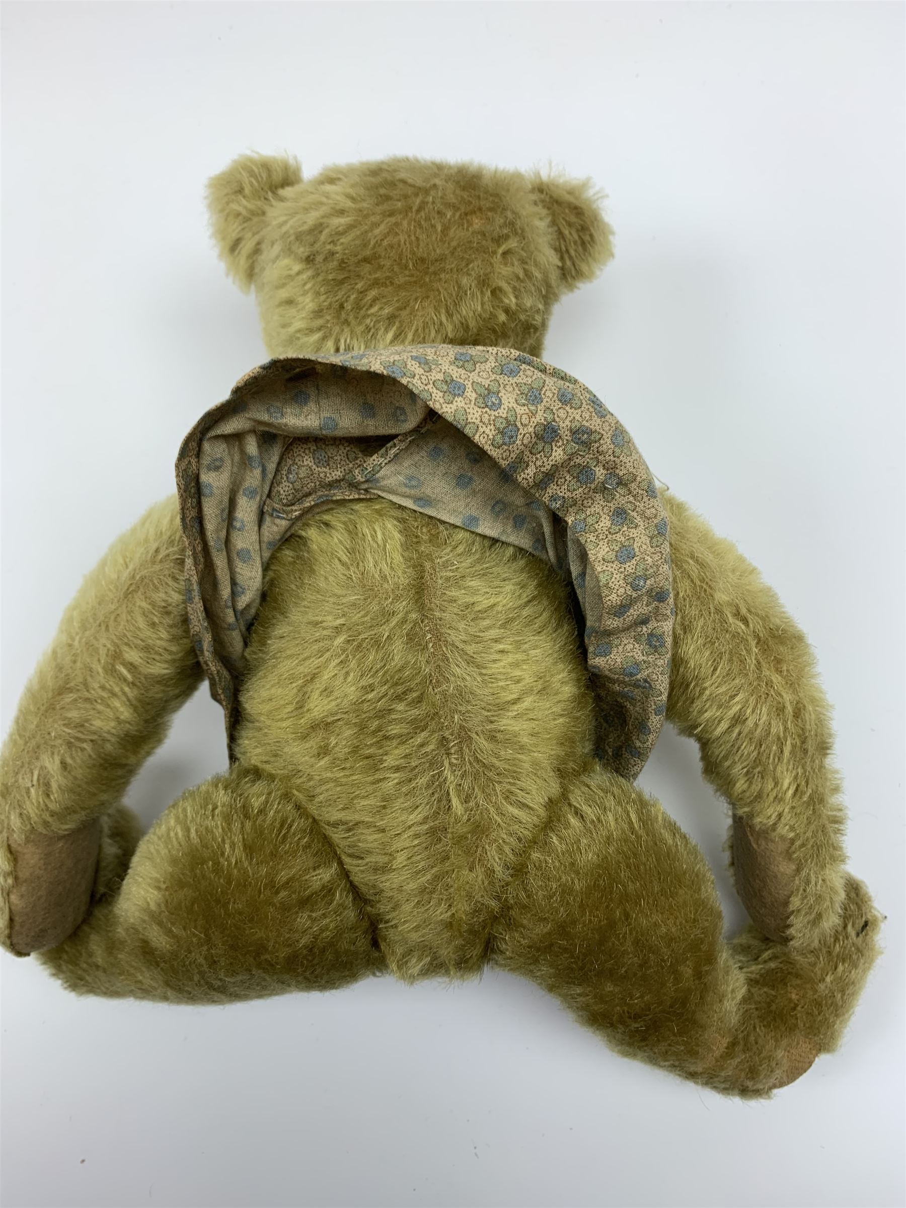 Early 20th century German Steiff teddy bear c1910 with wood wool filled humped back mohair body, swivel jointed head with black boot button eyes and horizontally stitched black nose and mouth, FF metal button to left ear, jointed elongated limbs with felt paw pads and black stitched claws H13