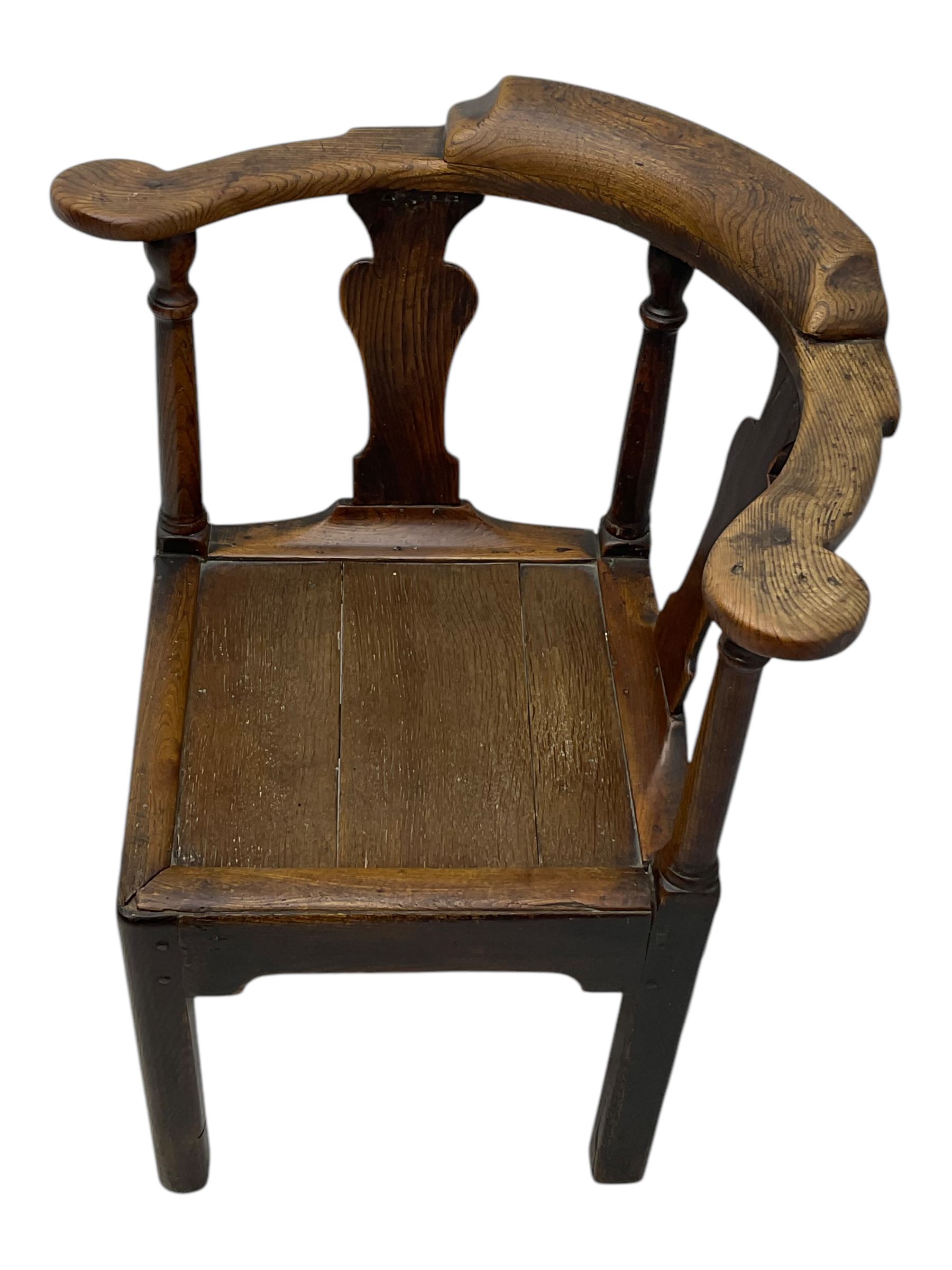 18th century oak corner elbow chair, the shaped cresting rail terminating to swept arm rests, supported by turned columns and vase-shaped splats, over square plank seat, raised on square-section supports