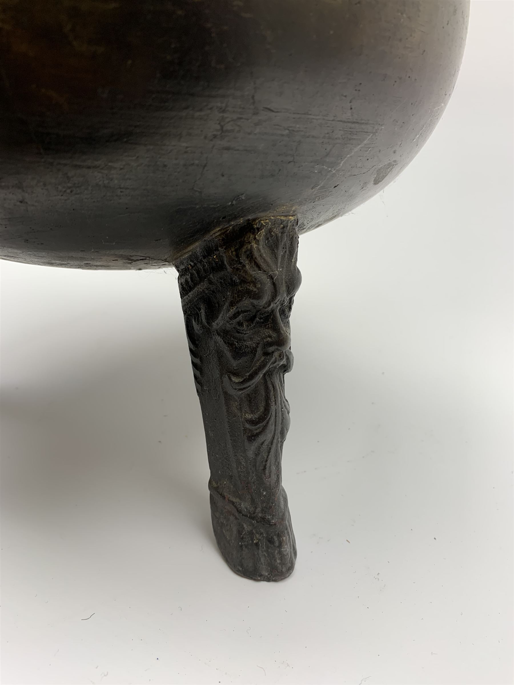 17th century bronze cauldron, probably German or Austrian, of bellied form with twin angular handles supporting a twisted handle, upon three splayed zoomorphic bearded mask feet, not including handle H30cm, rim D22cm