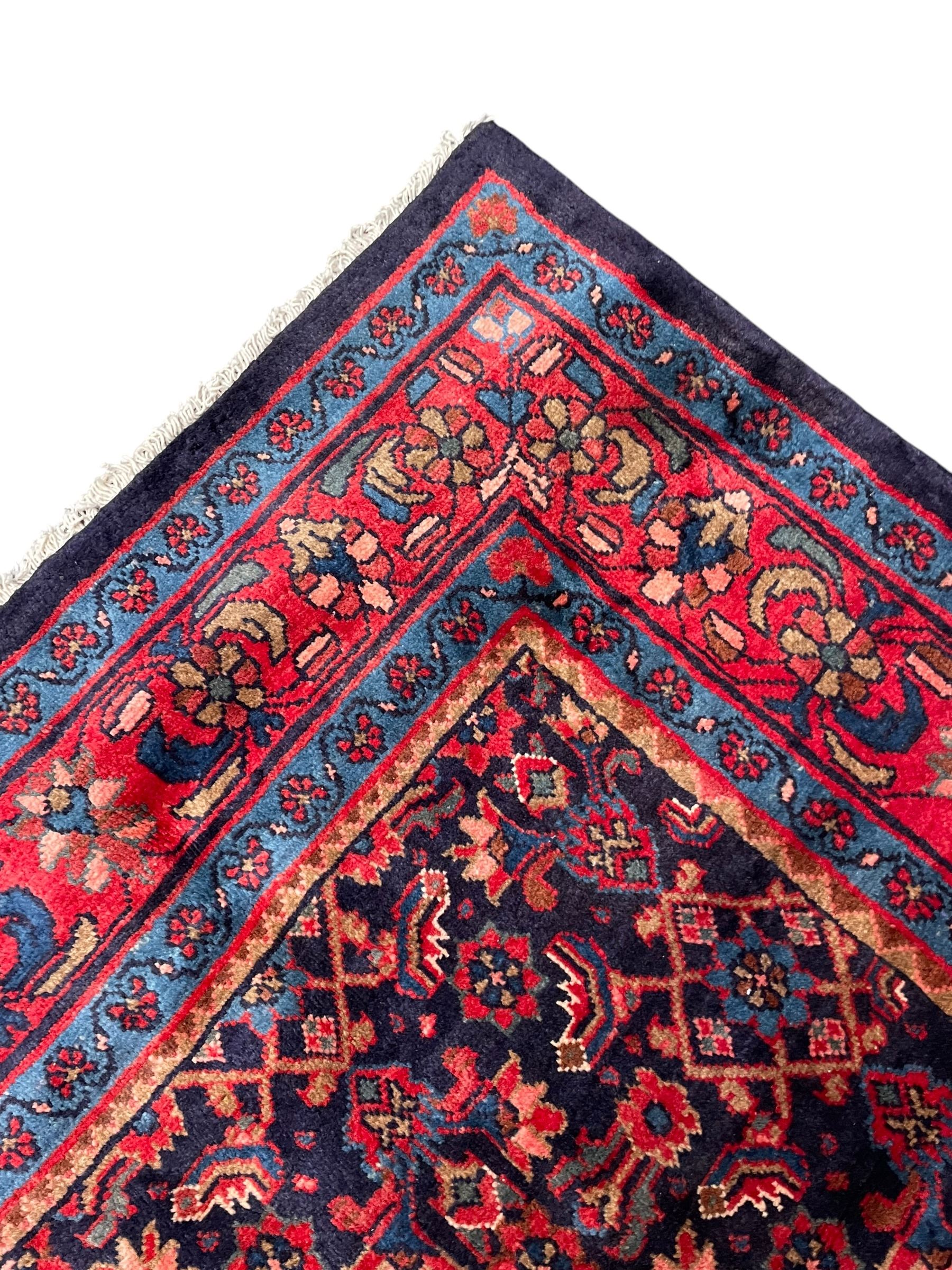 Persian indigo ground rug, the field decorated all over with floral Heratti motifs, crimson border with trailing stylised flower heads, within guard stripes