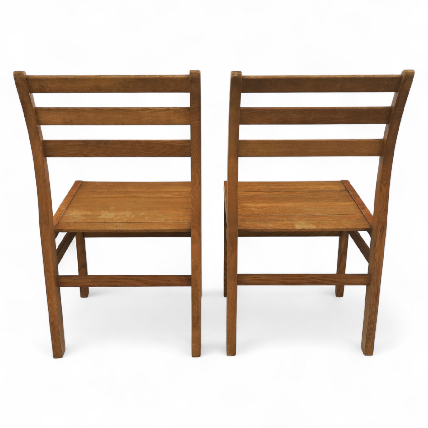 Treske of Thirsk - solid oak refectory dining suite, rectangular top with chamfered edge over trestle base united by a central stretcher, together with six matching slat back dining chairs, including two carvers, with panelled seats and square legs united by stretchers (H 87cm, W 62cm, D 57cm)
