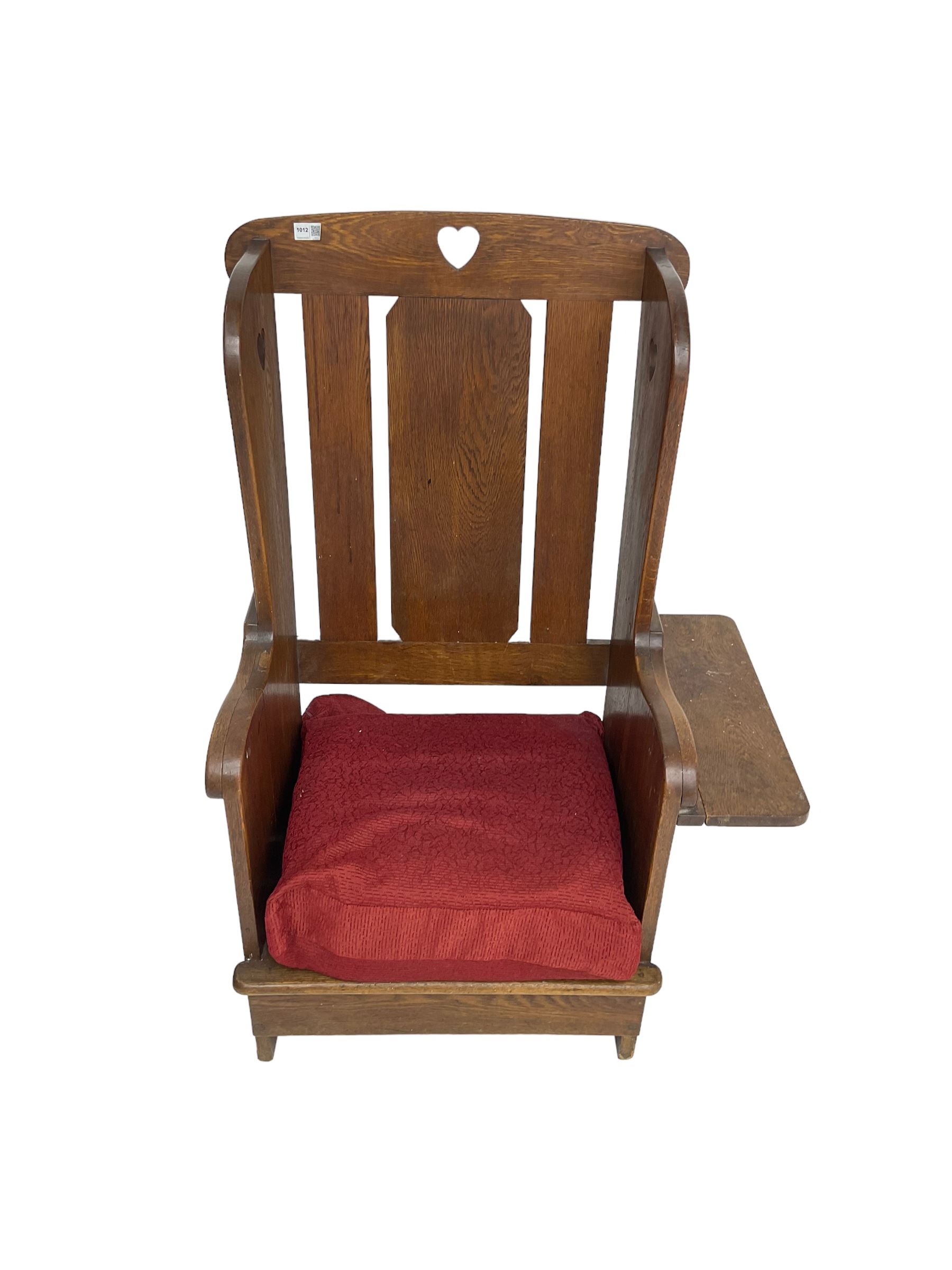 Arts and Crafts design oak reading wingback armchair, high back with pierced heart design, drop-leaf side table to one arm