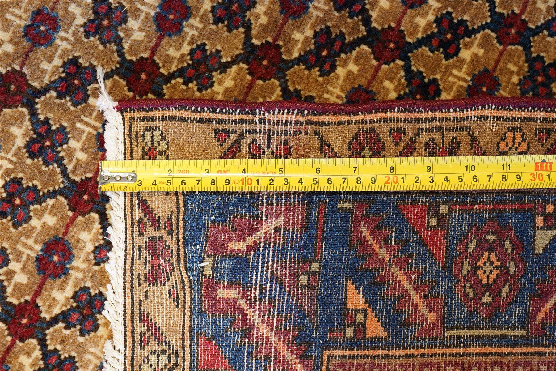 North East Persian Kurdie hand-knotted runner, camel ground with an all-over lattice of rosette motifs linked by angular vines, terminating in a stepped lozenge panel, with a madder red field, spandrels with geometric and zoomorphic devices, indigo main border of angular vines and repeating rosettes, flanked by narrow guard stripes, cotton fringe ends  