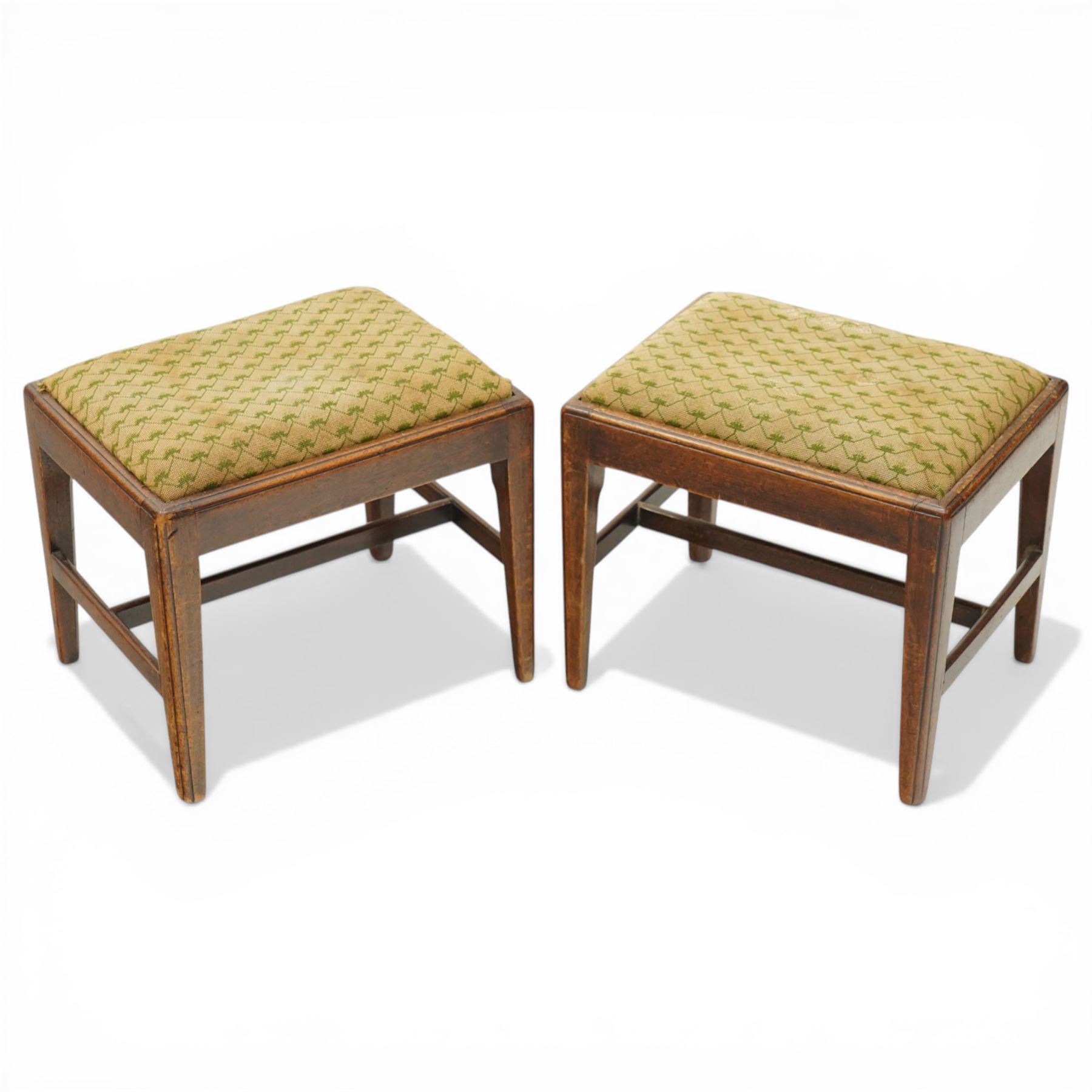 Pair of George III mahogany framed coaching stools, the drop-in seats upholstered in green and beige needlepoint fabric, raised on moulded and chamfered square tapering supports united by H-stretcher