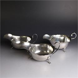 Three silver sauce boats, comprising pair of 1930s silver sauce boats, of typical form with shaped rim, scroll handle and upon three pad feet, hallmarked Viner's Ltd, Sheffield 1932 and a similar 1920s example with flying C scroll handle and upon three paw feet, hallmarked James Deakin & Sons, Sheffield 1923, tallest including handle H7.5cm