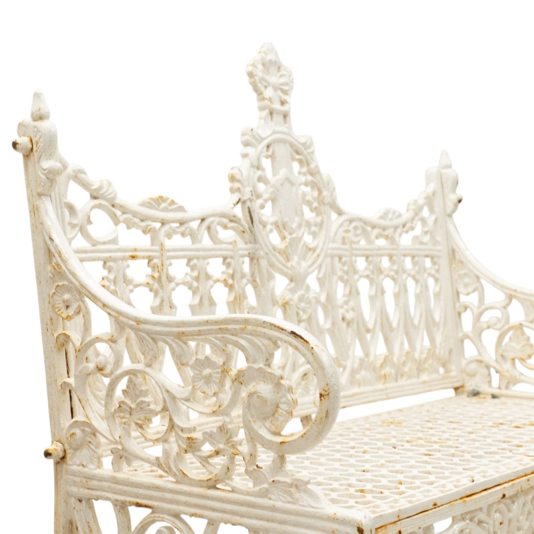 Victorian revival heavy cast iron garden bench, ornate back rest with scrolls, floral motifs and central crest, pierced lattice seat, curved arms and decorative legs, painted in antique white, in the Gothic Coalbrookdale style