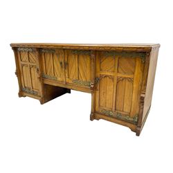 Late 19th century oak sideboard, fitted with two central cupboard doors flanked by two long cupboards enclosing drawer and shelf, the doors panelled and carved with arches and separated by shaped uprights