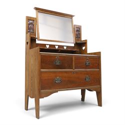 Shapland & Petter - oak mirrored dressing chest, tilted mirror flanked by tulip carved supports, shaped shelves with heart cut outs, above two short over one long drawers, with brass handles and stamped S & P on the locks, raised on shaped supports
