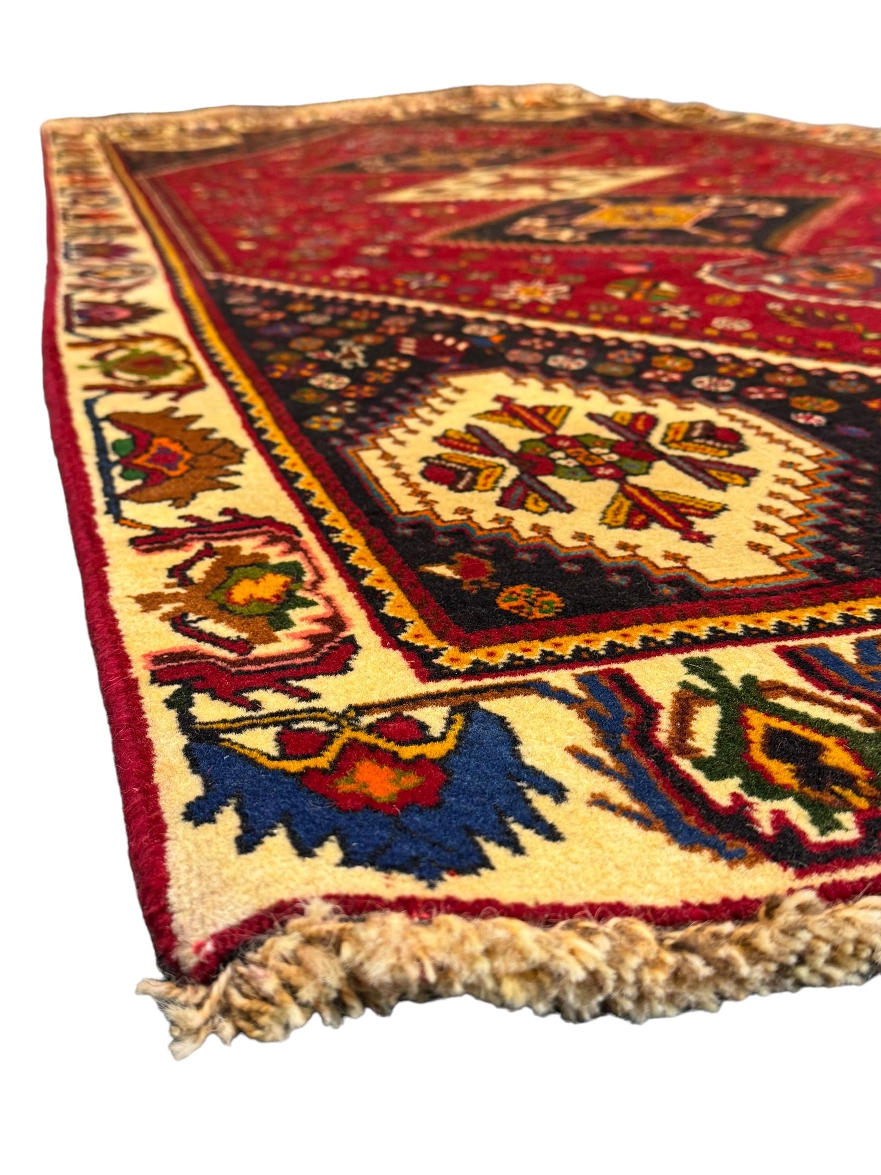 South West Persian Qashqai red ground runner, the crimson field decorated with three connected lozenges, surrounded by small stylised motifs of bird and plants, indigo spandrels with further stylised motifs, the border with repeating floral design 