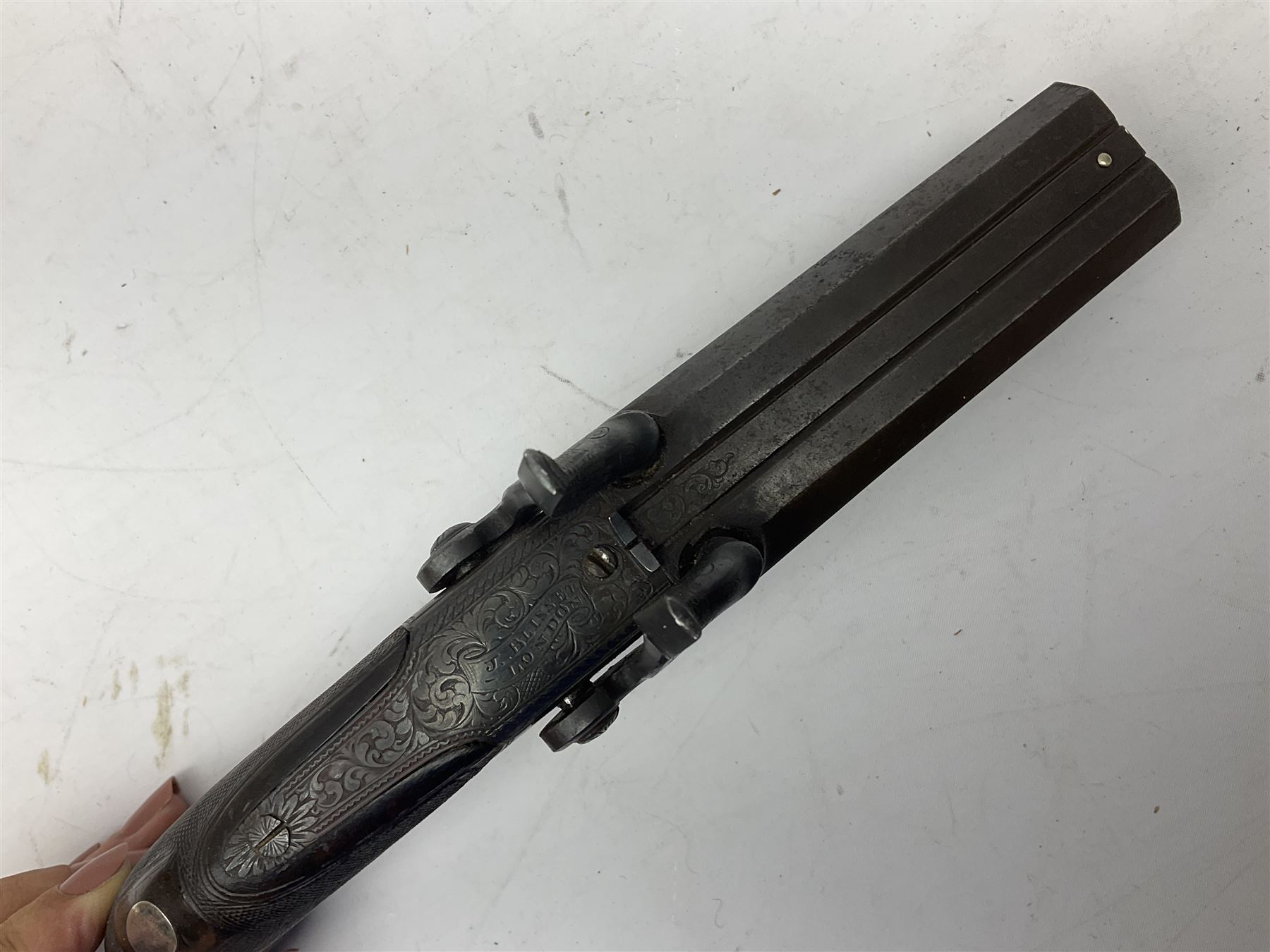Early 19c percussion double barrel Howdah pistol by J. Blisset London, c1840s, approximately 50 calibre, 10.5cm octagonal monobloc barrels with captive swivel ramrod under, finely chequered walnut stock, engraved hammers, lock plates, tang and trigger guard, butt plate with hinged cap compartment, vacant white metal oval escutcheon L25.5cm overall