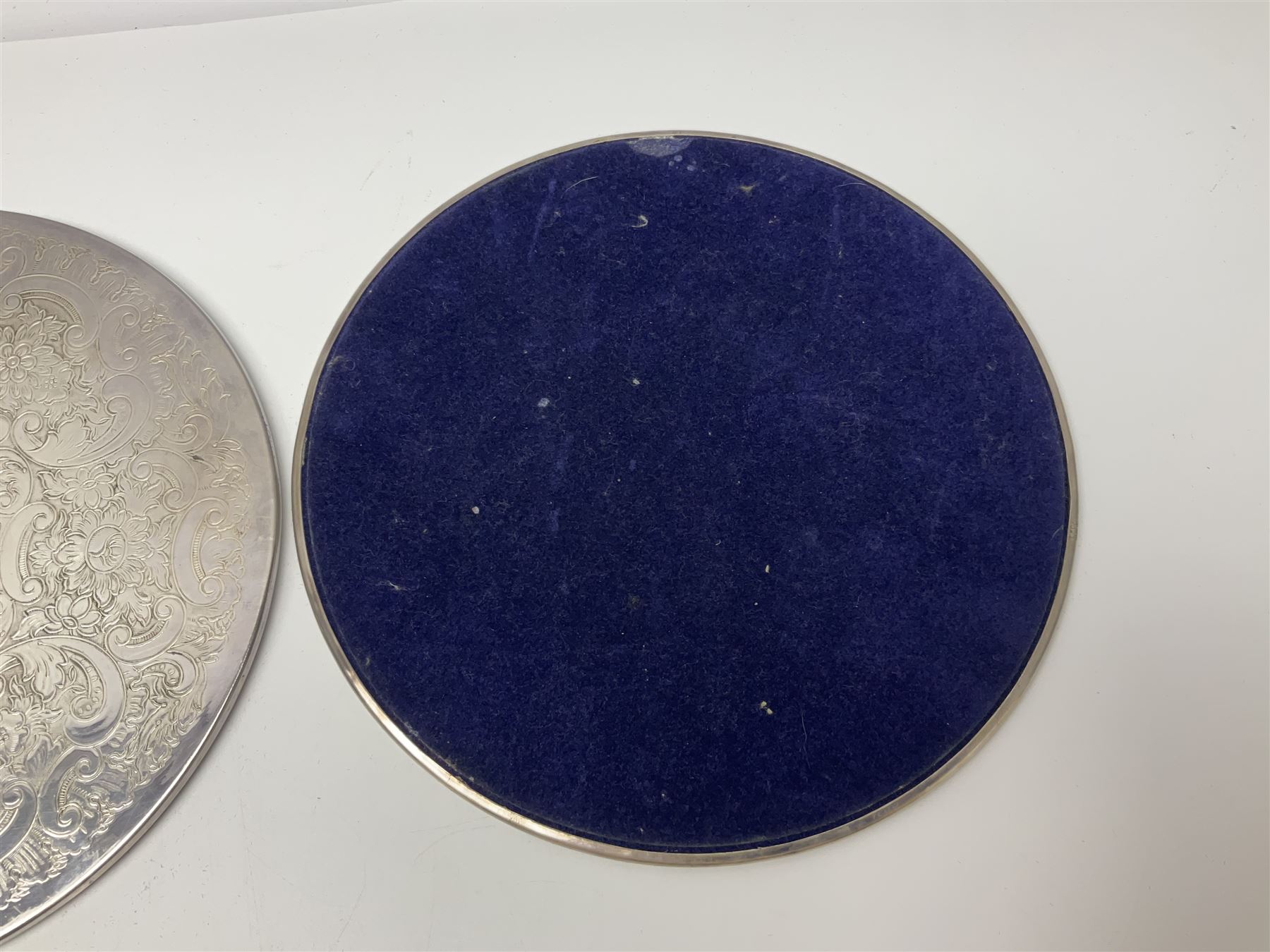 Set of eight silver plated placemats, each of circular form with engraved scroll and floral decoration, including two larger and six smaller examples, largest D23cm, in fitted case 