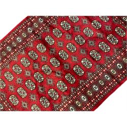 Persian Bokhara crimson ground rug, the field decorated with repeating Gul motifs and lozenges, the multi-band border with stylised plant motifs with black outlines
