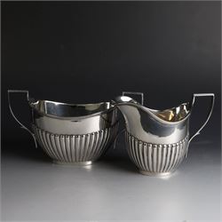 1920s silver three piece tea service, comprising teapot, twin handled open sucrier and milk jug, each of oval part fluted form, the teapot with Bakelite type handle and finial, hallmarked Cooper Brothers & Sons Ltd, Sheffield 1922