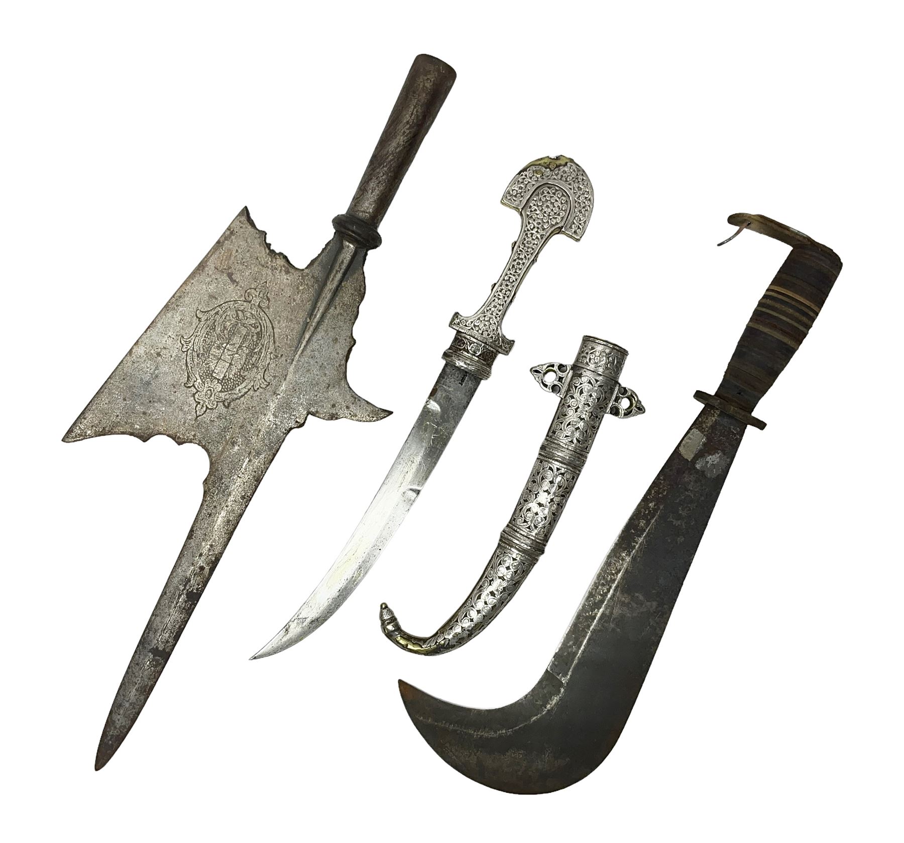 Moroccan jambiya dagger with 24.5cm plain curved blade stamped LONDON to the ricasso area, the hilt and scabbard overlaid with plain sheet brass to the back and ornate silver coloured metal to the front; waisted grip and arched pommel; two pyramid mounts to the scabbard L41cm overall; large billhook with curving blade and stacked leather washer grip; and a reproduction halberd blade (3)