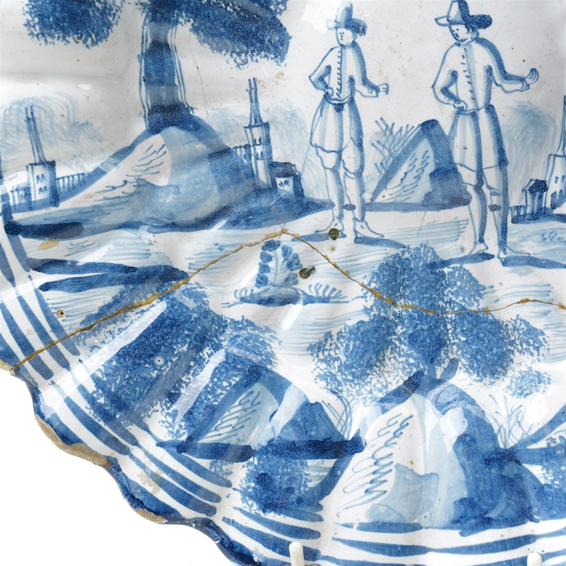 18th century Dutch Delft plate of fluted design decorated in blue and white with figures in a landscape D29cm and a Dutch Delft vase decorated in blue and white with oriental flowers H21cm (2)