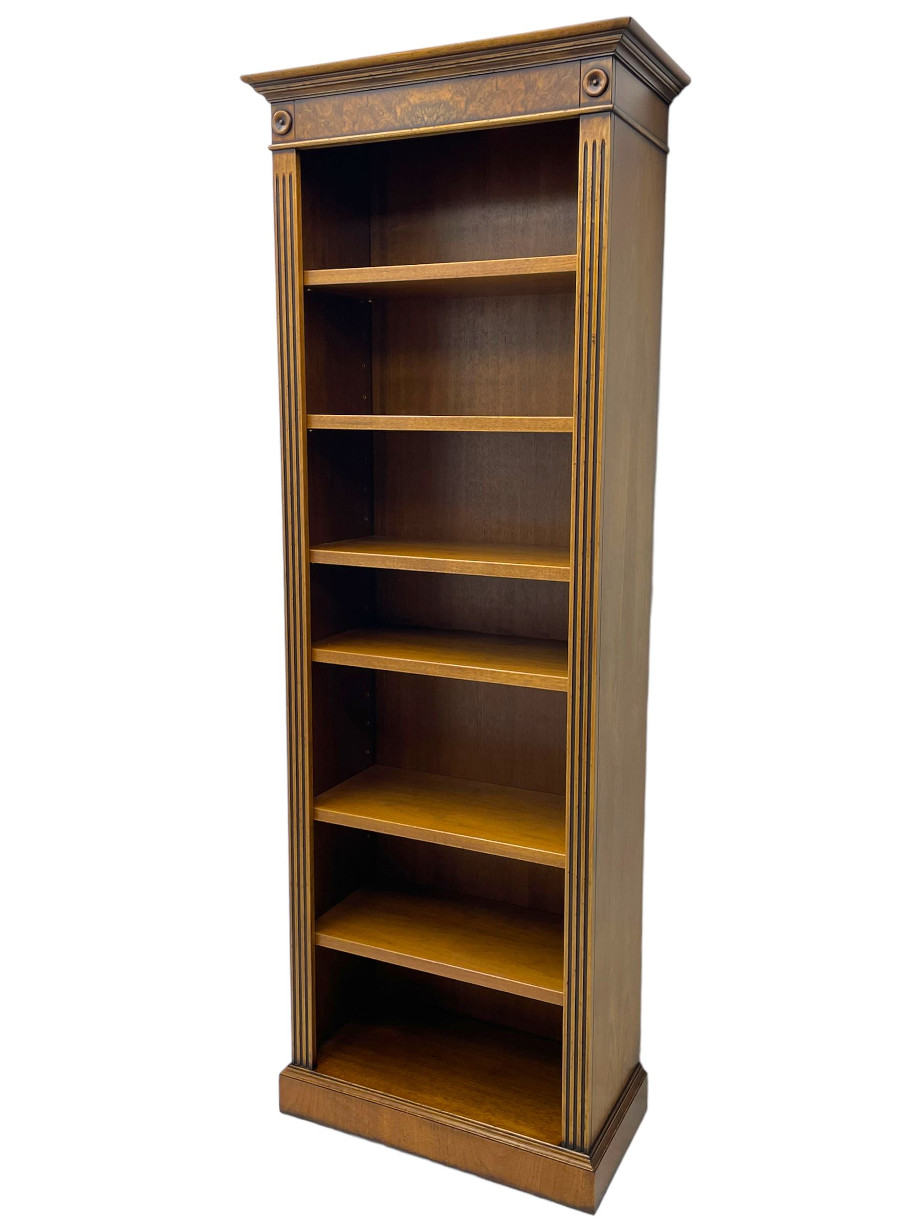 Georgian design walnut open bookcase, projecting cornice over figured banded frieze flanked by roundels, fitted with six adjustable shelves with flanking fluted uprights, on skirted base