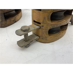 Three ship pulleys comprising wooden block double with swivel eye marked 'wooden block 240mm bduble rope: 22mm',  wooden block double with upset shackle and wooden block with stiff swivel hook, largest example L50cm