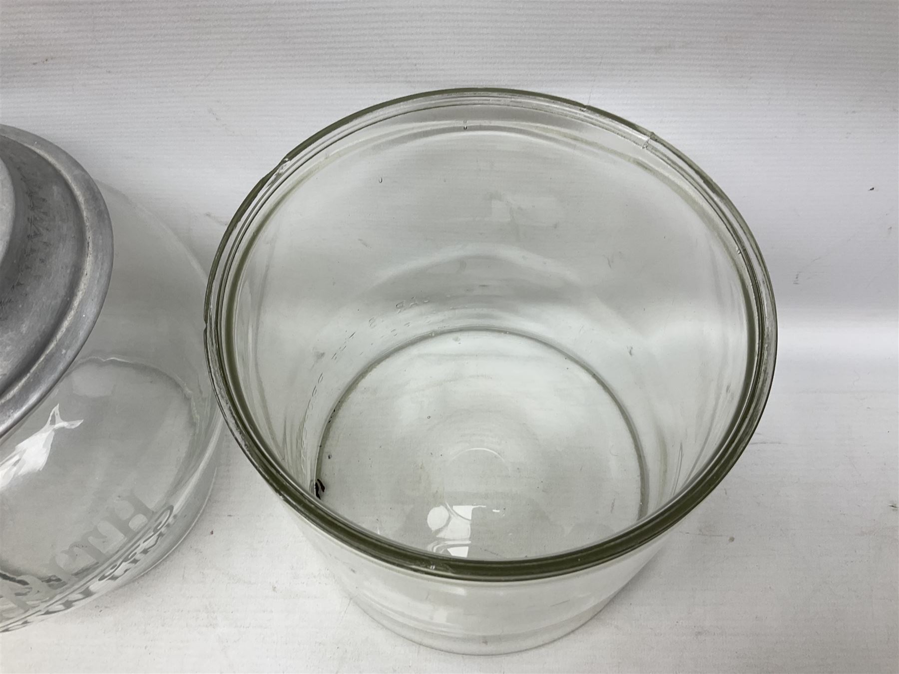Early 20th century Meredith & Drew shop advertising glass biscuit barrel, the body of tapering form with etched lettering with original aluminium lift off lid, together with a Smith's Crisps glass jar and cover with red and dark blue letterin, tallest H25cm (2)