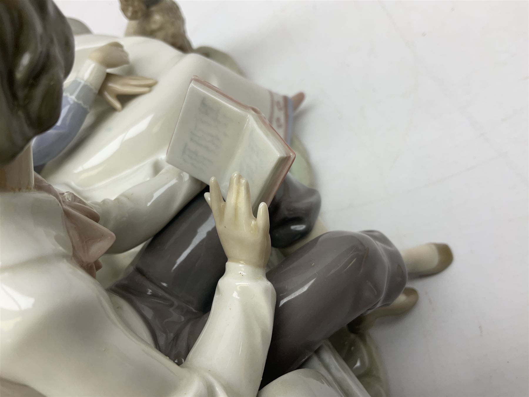 Lladro figure, Poetry of Love, modelled as a boy seated reading from a book next to a girl on garden bench with a dog at her feet, sculpted by Regino Torrijos, with original box, no 5442, year issued 1987, year retired 1998, H22cm